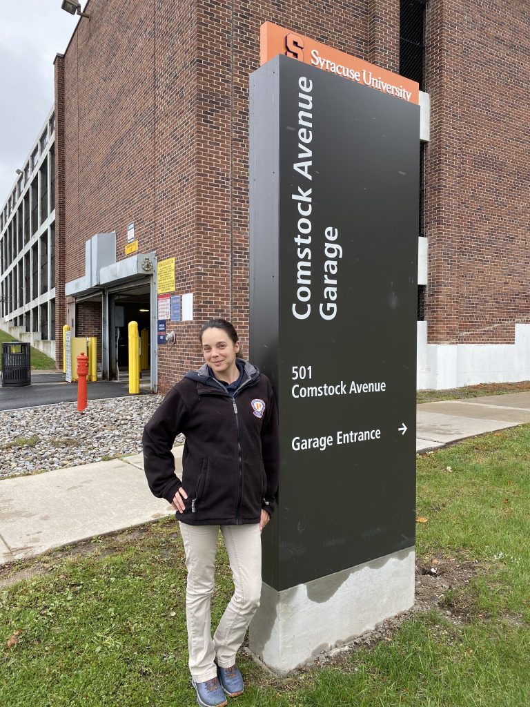 Woman Standing Next to Comstock Ave. Garage Sign